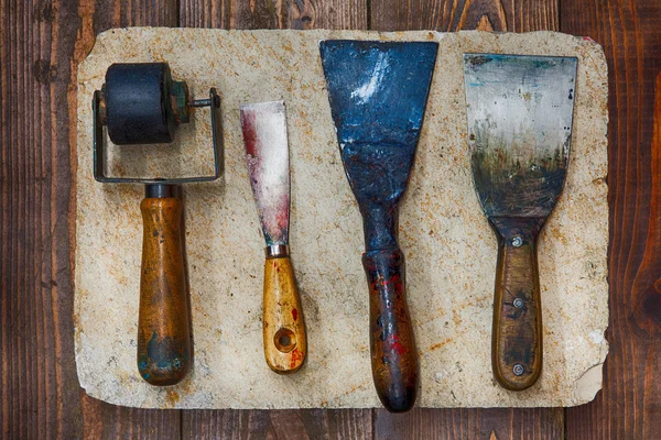 Retro design tools for artist workshop: rubber roller, different size putty knives on stone plate and wooden background. Techical service diy tools, decorator accessories concept. soft focus, up view