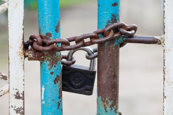 Closed gates with padlock and iron chain. metallic textures, shabby turquoise paint surface. macro view. Security concept vintage lock. soft focus