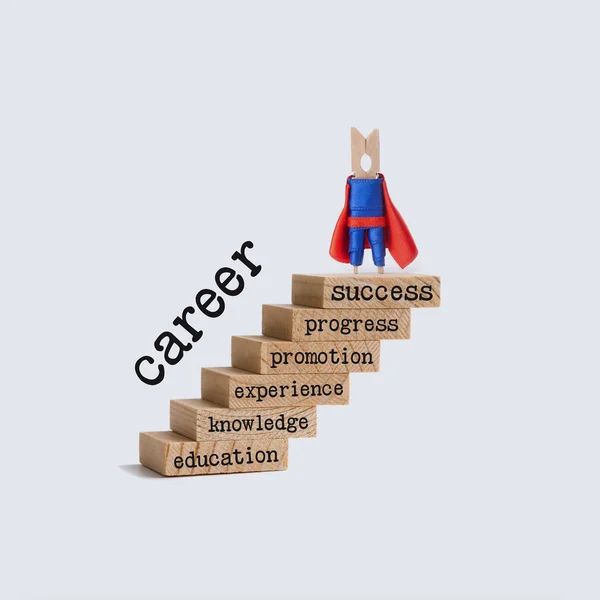 Career ladder growth concept. Superhero character on top of the wooden steps. vintage staircase with words: education, knowledge, experience, promotion, progress, success. white background.