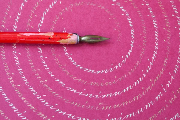 Red nib pen on pink paper textured background, abstract letters pattern. macro view, shallow depth of field