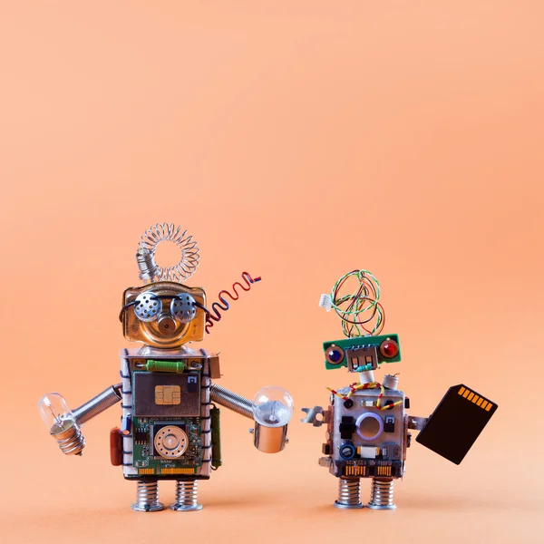 Robot friends concept. Pair robotic circuit socket toy mechanism characters with black microchip lamp bulbs. Funny faces, blue red eyes and glasses. Copy text, light gradient peach color background