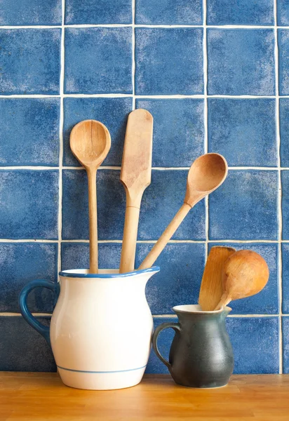 Kitchen still life. interior with retro accessories. Blue tiles ceramic wall background, pitchers vintage wooden spoons.