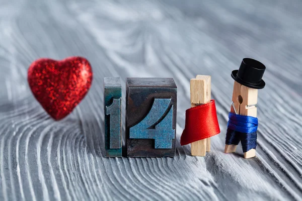 Love concept. Valentines day. 14 february. Romantic couple. Man, woman and read heart. Clothespins. (Soft focus, 14 written with colored vintage letterpress)