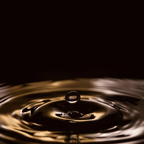 Liquid drops. splashing. gold, black, white waves. Black background.