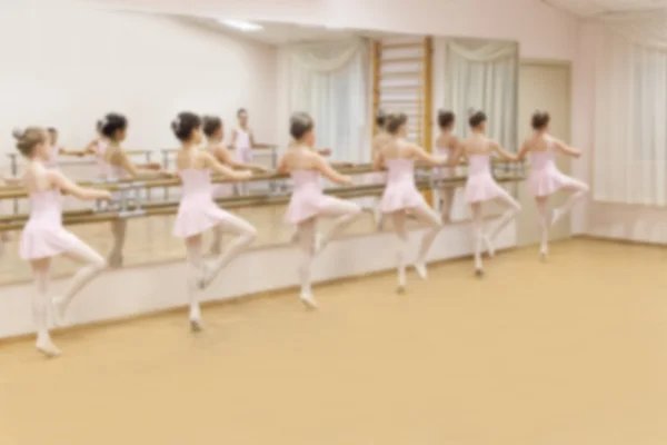 Blurry image group of six young ballerinas standing in row and practicing ballet. girls, dancer exercises at training hall. Soft focus, copy space