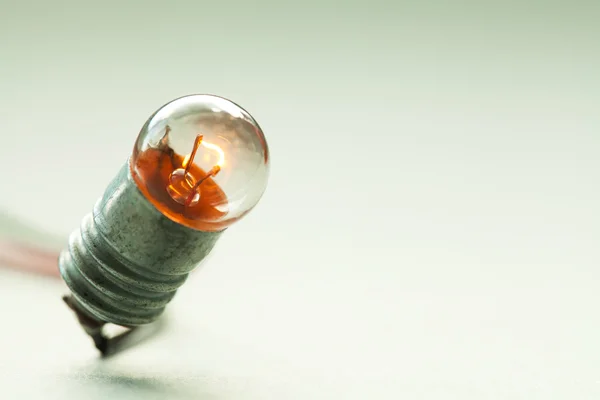 Glowing light bulb. Vintage design filament lamp macro view. Soft colors background. Shallow depth of field. Copy space