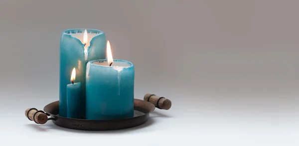 Romantic still life with turquoise different size candles on vintage metal plate. natural flame and drips. Beige gradient background. Holiday invitation, romance concept card template. copy space