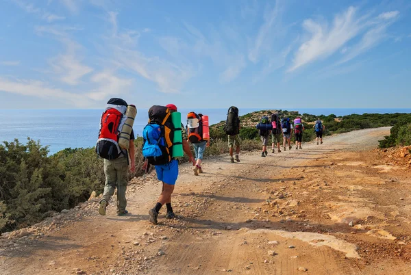 Group of tourists with large backpacks are on road sea
