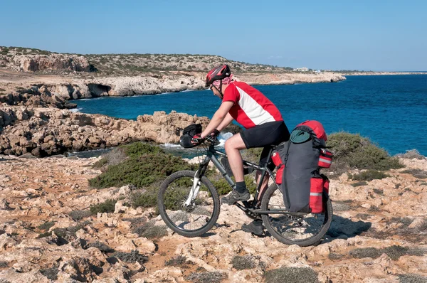 Mountain bike rides along the steep seashore.