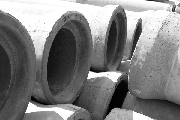 Industrial concrete drainage pipes stacked for construction. New tubes black and white