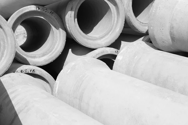 Industrial concrete drainage pipes stacked for construction. New tubes black and white