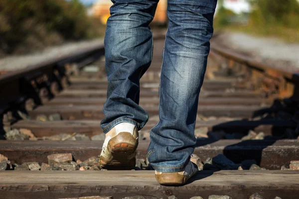 Closeup of person\'s feet walking on railway tracks