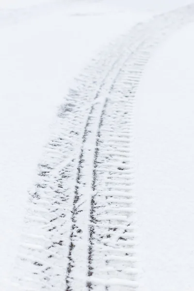 Car tire tracks on snowy asphalt