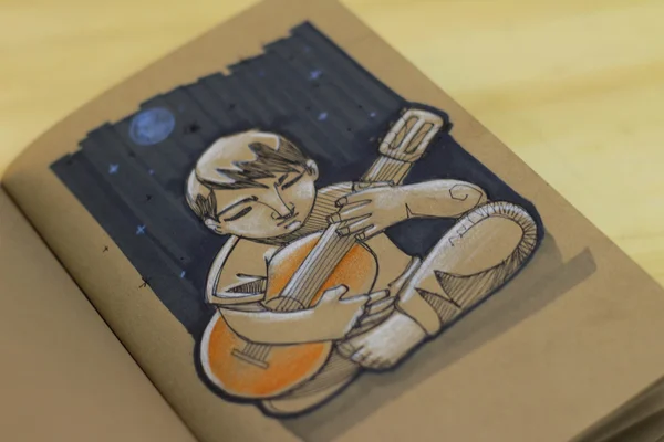 Musician playing guitar drawing on a notebook