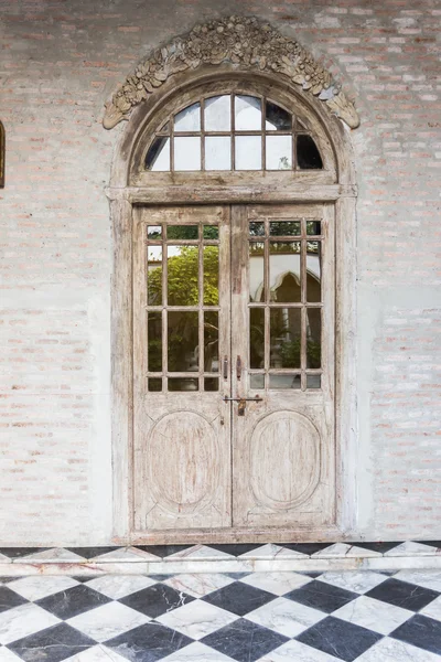 The wooden front door of a home with glass panels to each side a