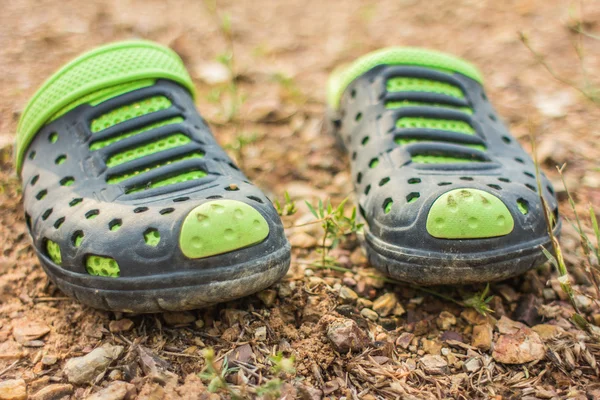 Pair of green slippers dirty on the soil.