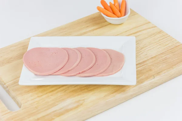 SLICED BOLOGNA SALAMI ON THE WOODEN BOARD.