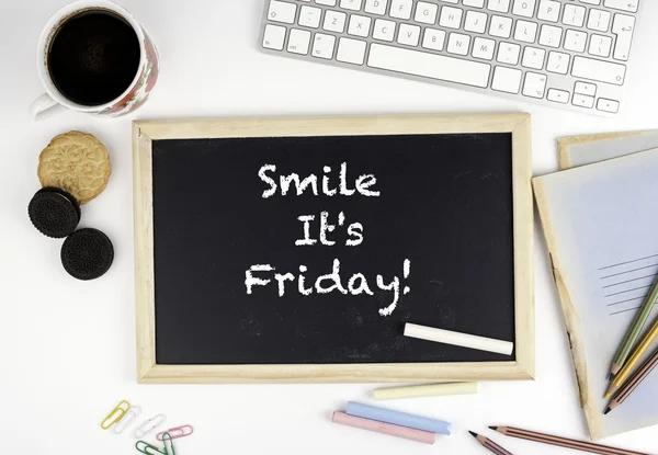 Chalkboard on office desk with text: Smile It\'s Friday