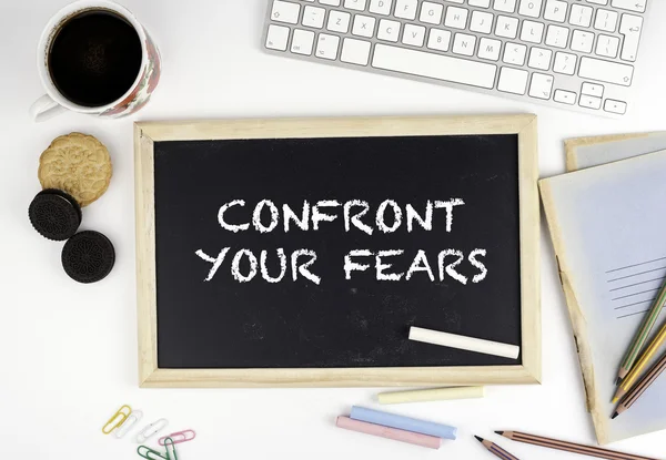 Chalkboard on office desk with text: Confront Your Fears