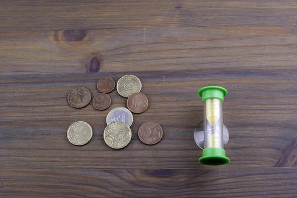 Hourglass and euro small change on wooden background