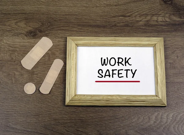 Medical plasters and wooden frame with text: Work Safety