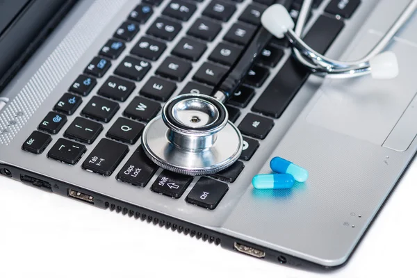 Stethoscope with pills on laptop keyboard