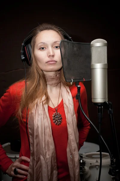 Female singer with headphones recording in studio