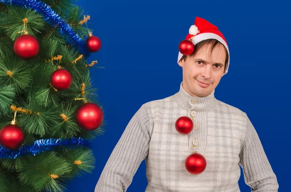 The man costs near an elegant New Year tree having dressed on hi