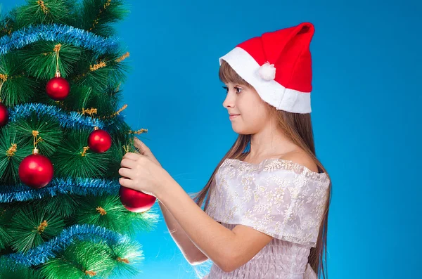 The girl hangs up a toy on a fir-tree