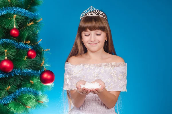 The girl with long hair in a red cap costs near a New Year tree