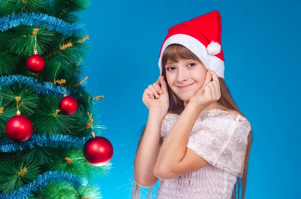 The girl with long hair in a red cap costs near a New Year tree
