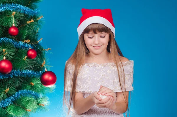 The girl with long hair in a red cap costs near a New Year tree