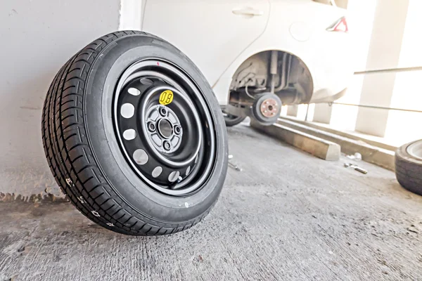 Car mechanic changing tire, changing tire with wheel wrench.