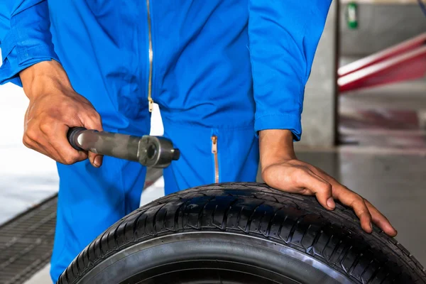 Mechanic holding a wrench and car wheel in car garage service