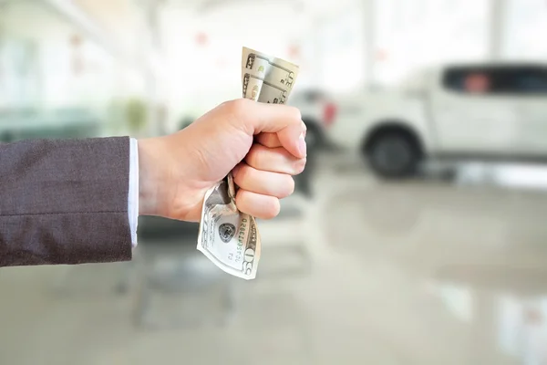 Businessman grasping money and giving away in showroom blurred background