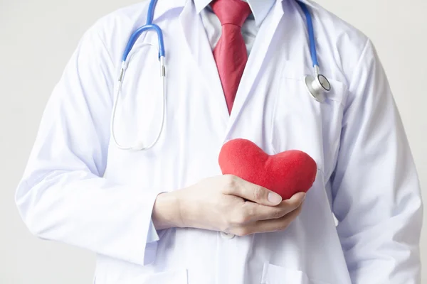 Doctor showing compassion and support holding red heart onto his chest in his coat