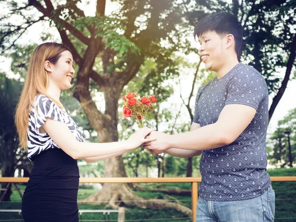 Asian couple handing a bunch of roses in the public park - in vintage tone