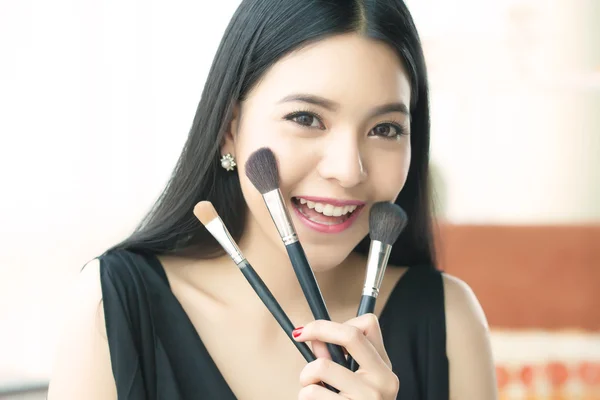 Asian woman holding brushes - beauty makeup concept