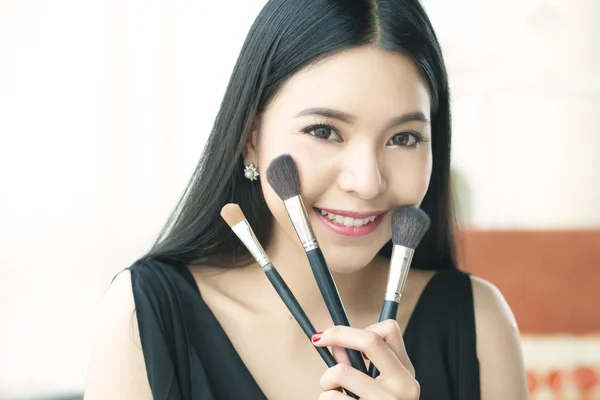 Asian woman holding brushes - beauty makeup concept