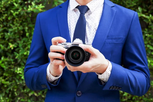 (Close-up) Young professional photographer taking photos in green bushes outdoor background