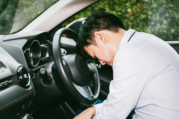 Sleeping and tired businessman with fatigue on steering wheel in the car - business-related tiredness