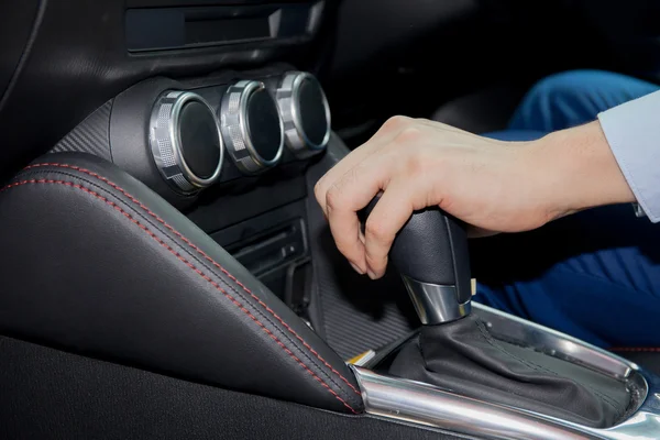 Human hand shifting automobile gear inside the car
