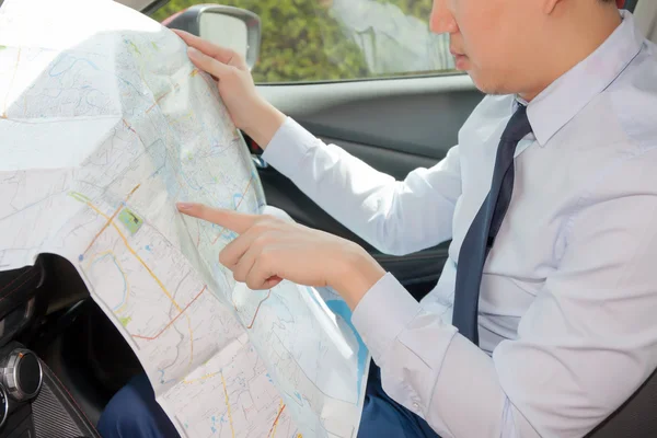 Young man lost direction and looking at map in car to plan his journey.