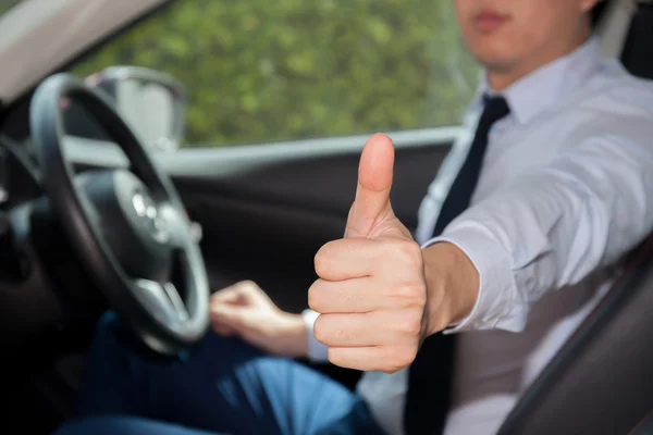 Happy man in casual suit giving thumbs up to someone in the car