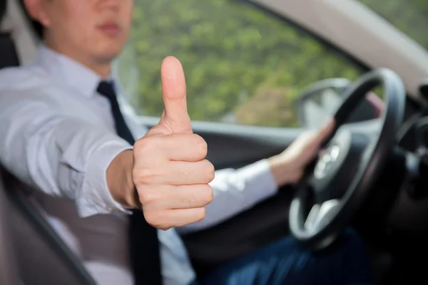 Happy man in casual suit giving thumbs up to someone in the car