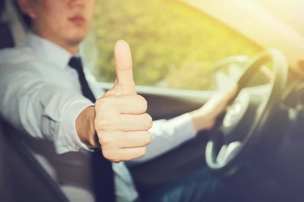 Happy man in casual suit giving thumbs up to someone in the car