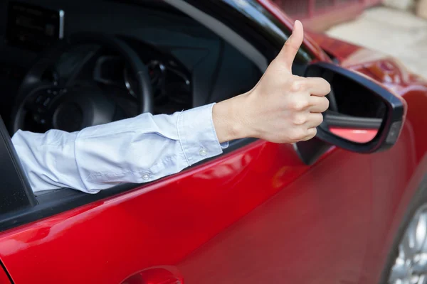 Happy man in casual suit giving thumbs up to someone in the car