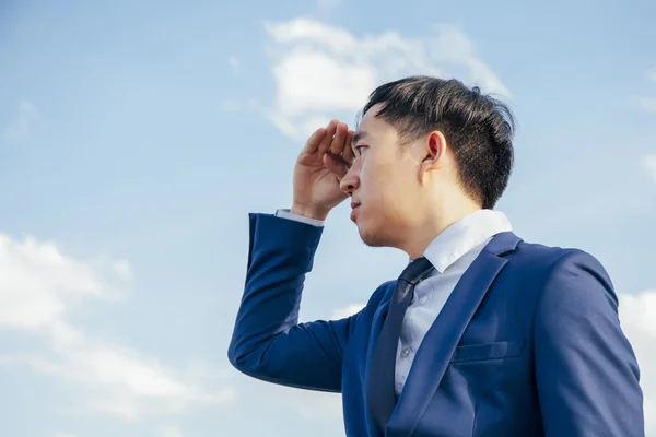 Asian business man searching or looking for opportunity over blue sky background