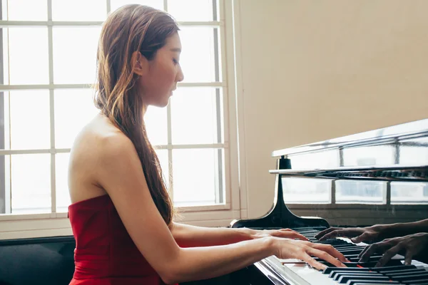 Asian woman playing piano in window background with light coming