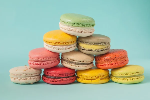 Pile of colorful macaroons stacked up like a tower in blue turquoise pastel isolated background